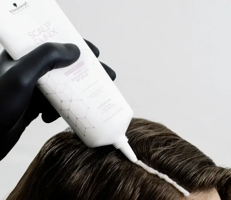 Haarpflegeprodukt wird auf dunkles Haar aufgetragen