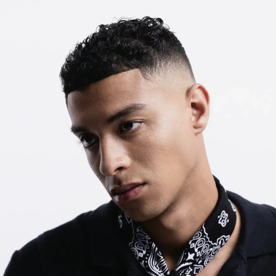 Mann mit kurzem, lockigem Haar und sauberem Fade Cut