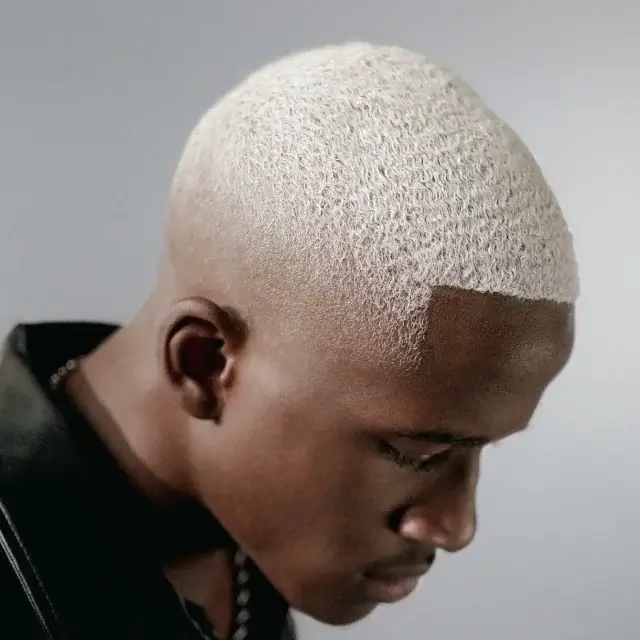 Mann mit sehr kurzem, platinblondem Haar und präzisem Fade Cut