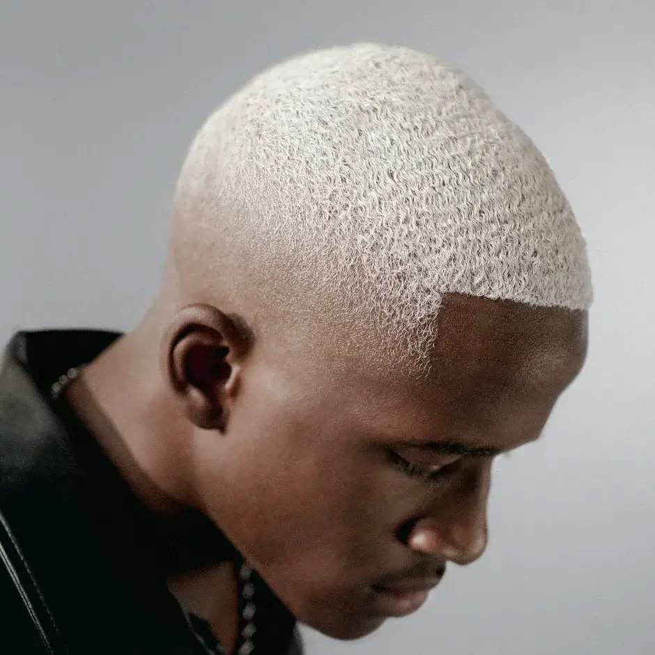Mann mit sehr kurzem, platinblondem Haar und präzisem Fade Cut