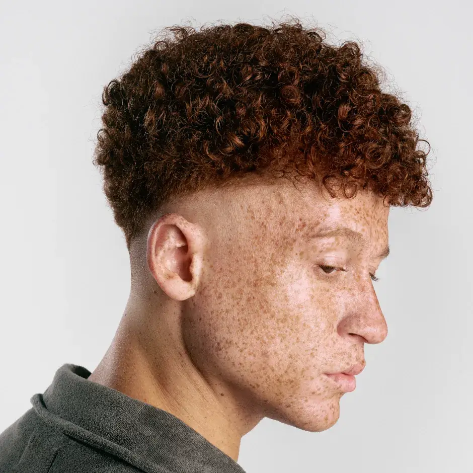 Mann mit kurzen, definierten Locken und ausgeblendeten Seiten